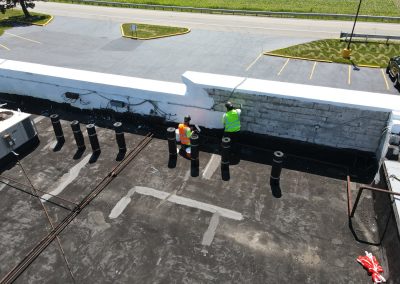 Contractors painting a roof white