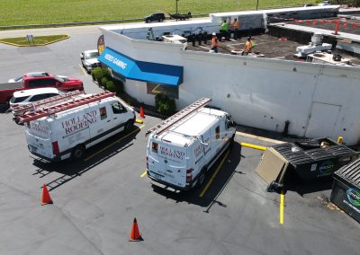 Holland Roofing vans and crew on a flat roof