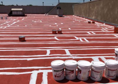 Buckets sitting on top of a commercial roof getting coated