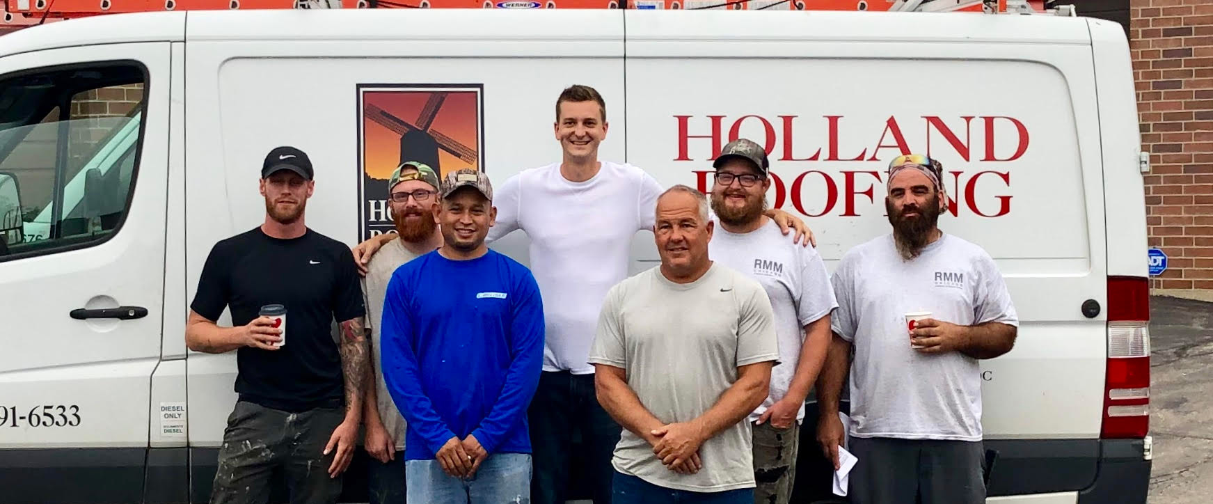 Holland Roofing team in front of company trucks
